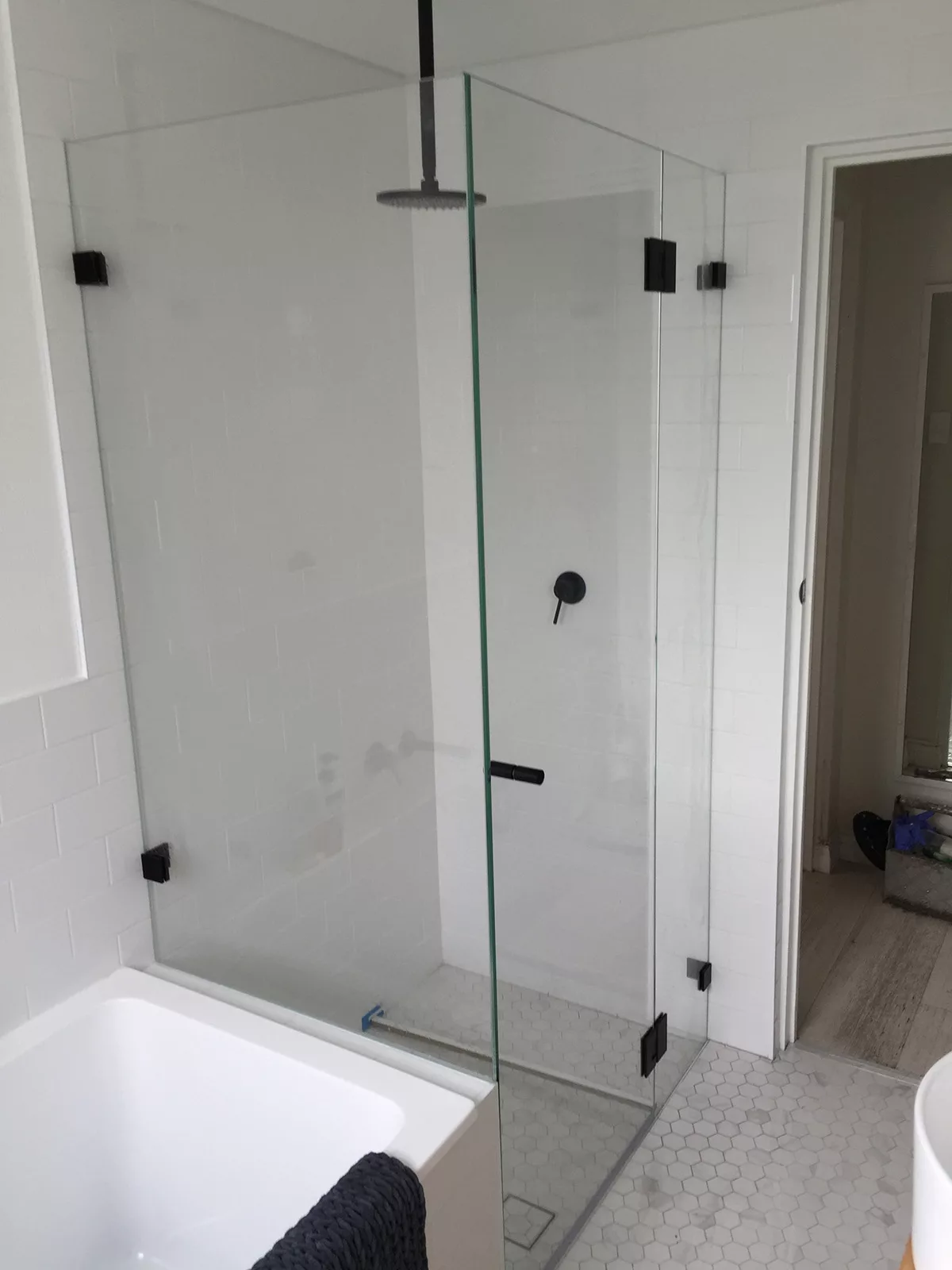 Frameless corner shower screen over bath Frameless corner shower screen over bath